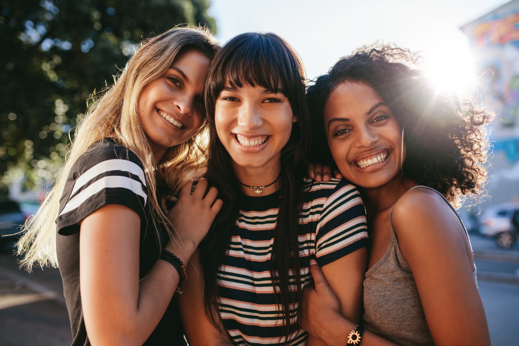 Three beautiful smiling girl friends standing together